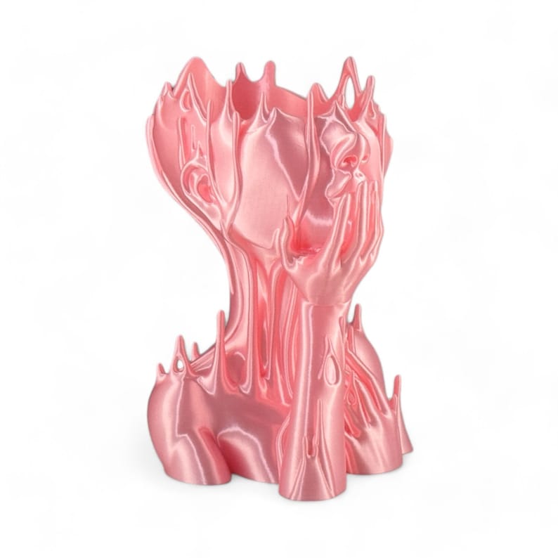 May include: A pink, abstract sculpture of a human head with a flowing, melted appearance. The sculpture has a smooth, glossy finish and appears to be made of plastic.