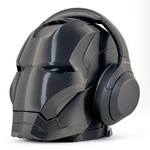 K&ouml;nnte beinhalten: Ein schwarzer Iron Man Helm mit einem schwarzen Sony Kopfh&ouml;rer darauf. Die Kopfh&ouml;rer haben ein kupferfarbenes Logo mit der Aufschrift "SONY".