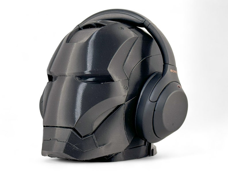 K&ouml;nnte beinhalten: Ein schwarzer Iron Man Helm mit einem schwarzen Sony Kopfh&ouml;rer darauf. Die Kopfh&ouml;rer haben ein kupferfarbenes Logo mit der Aufschrift "SONY".