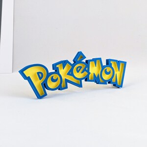 May include: A blue and yellow 3D printed word "Pokemon" with a stylized font.