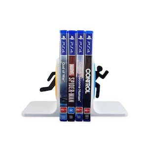 May include: A white bookend shaped like a running figure holding four video game cases. The cases are for the PlayStation 4 and feature the games "God of War", "Marvel's Spider-Man", "Detroit: Become Human", and "Control".