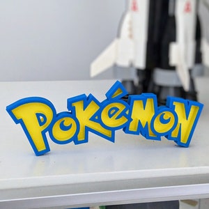 May include: A blue and yellow 3D printed sign that reads "Pokemon".