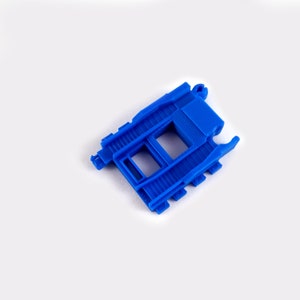 May include: Blue plastic train track piece with a raised section and two slots.