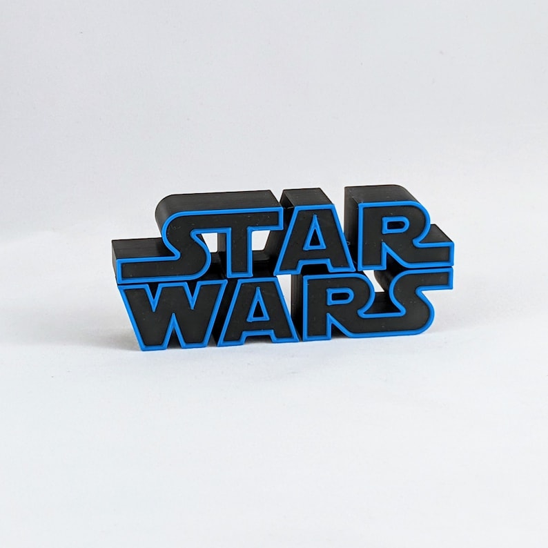 May include: Black plastic "Star Wars" logo with blue outlining. The logo is made of individual letters that are connected together.