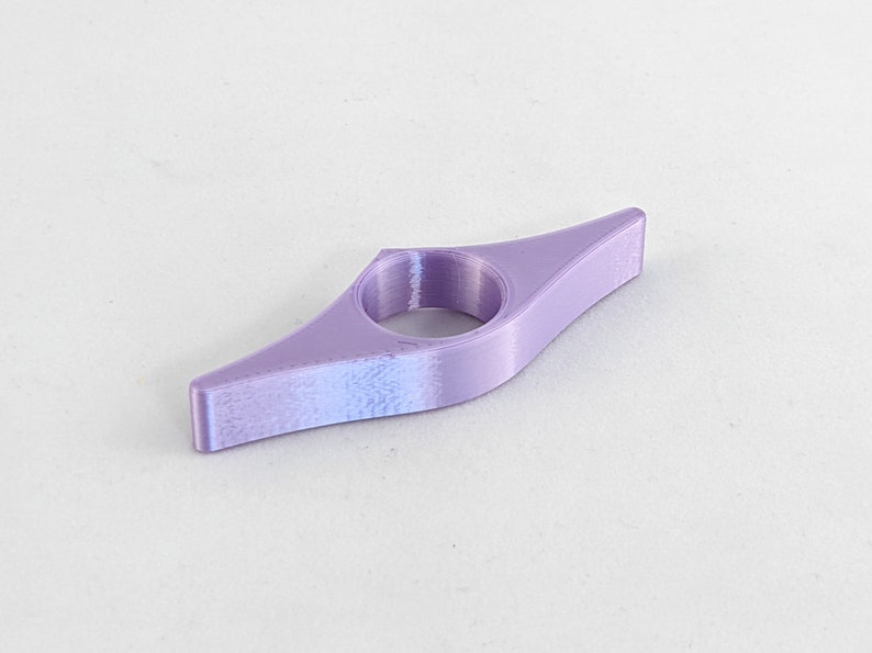 Peut inclure: Un marque-page en plastique violet en forme de livre. Le marque-page a un trou au centre pour maintenir une page.