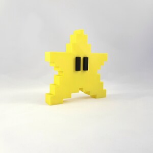 May include: A yellow star-shaped figurine with black eyes. The figurine is made of a blocky, pixelated style.
