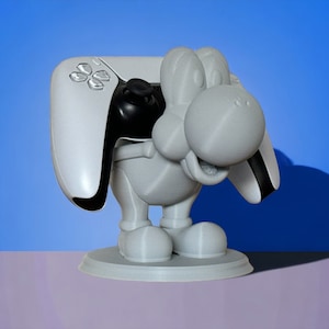 May include: A white 3D printed figurine of a cartoon character holding a white and black video game controller. The figurine is standing on a round base.