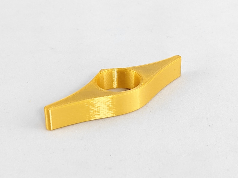Peut inclure: Un marque-page en plastique de couleur dor&eacute;e en forme de larme avec un trou rond au centre.