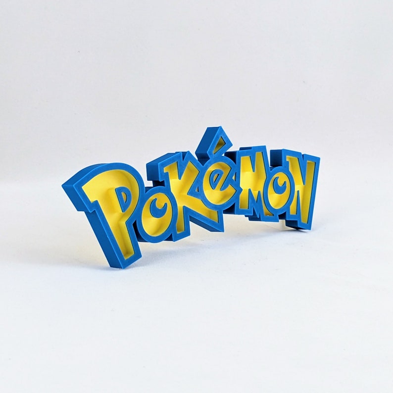 May include: A blue 3D plastic word that reads "Pokemon" with yellow letters. The letters are outlined in blue.