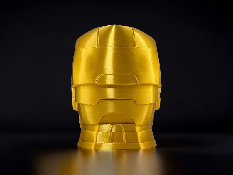 K&ouml;nnte beinhalten: Eine goldfarbene, 3D-gedruckte B&uuml;ste eines Roboterkopfes mit Visier.