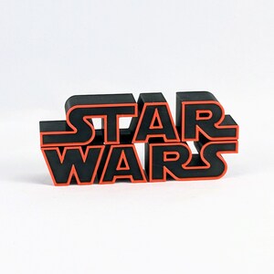 May include: Black 3D plastic "Star Wars" logo with red outline.