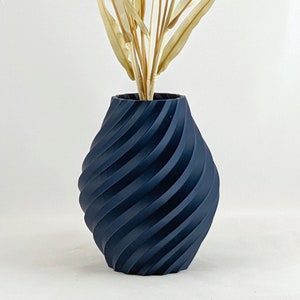 K&ouml;nnte beinhalten: Eine dunkelblaue Keramikvase mit einem wirbelnden, strukturierten Design. Die Vase ist leer.