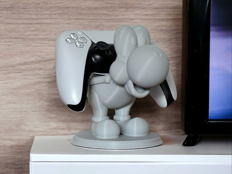 Yoshi-themed controller holder made of grey, designed to securely hold video game controllers.