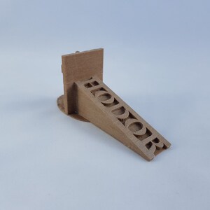 May include: A brown 3D printed doorstop with the word "Hodor" printed on the side.