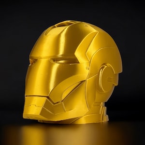 K&ouml;nnte beinhalten: Eine goldfarbene, im 3D-Druck hergestellte B&uuml;ste von Iron Mans Kopf. Die B&uuml;ste ist detailliert und hat eine metallische Oberfl&auml;che.