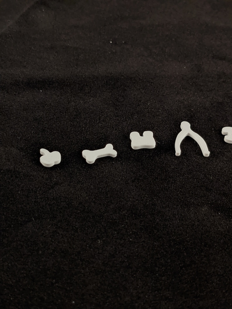 May include: A set of six white plastic cookie cutters in various shapes, including an apple, bone, house, pretzel, and two other shapes.