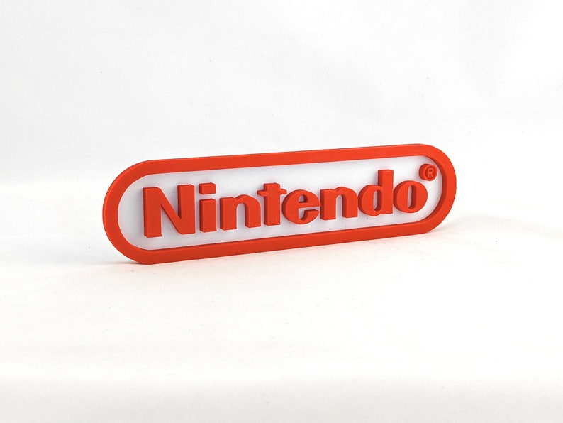 May include: A red and white plastic sign with the word "Nintendo" in red letters and a registered trademark symbol.