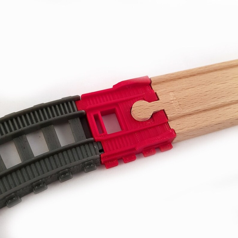 K&ouml;nnte beinhalten: Nahaufnahme einer Holzbahn mit einer roten Plastik-Weiche. Die Weiche hat einen kleinen Holzhebel, der bewegt werden kann, um den Zug auf die eine oder andere Strecke zu lenken.