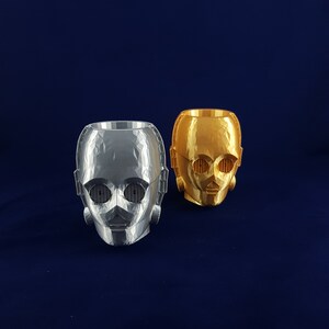 May include: Two 3D printed planters shaped like the head of C-3PO from Star Wars. One planter is silver and the other is gold.
