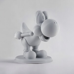 May include: A white 3D printed figurine of a cartoon dinosaur character with a large head and a wide smile. The figurine is standing on a circular base.