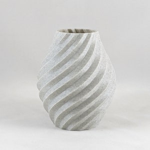 May include: A white ceramic vase with a swirling, textured design. The vase is a modern, contemporary style.