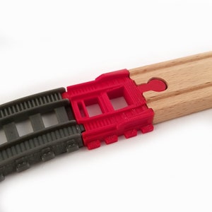 K&ouml;nnte beinhalten: Ein rotes und graues Holz-Eisenbahnset mit einem gebogenen Gleisst&uuml;ck und einem geraden Gleisst&uuml;ck. Das gebogene Gleisst&uuml;ck hat einen roten Plastikbr&uuml;ckenabschnitt mit zwei &Ouml;ffnungen.