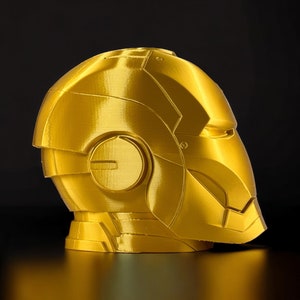 K&ouml;nnte beinhalten: Ein goldfarbener 3D-gedruckter Helm mit einem detaillierten Design. Der Helm hat eine glatte, metallische Oberfl&auml;che und scheint aus Kunststoff zu sein.