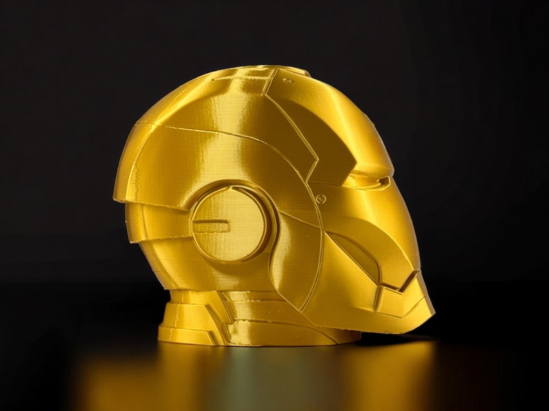 K&ouml;nnte beinhalten: Ein goldfarbener 3D-gedruckter Helm mit einem detaillierten Design. Der Helm hat eine glatte, metallische Oberfl&auml;che und scheint aus Kunststoff zu sein.