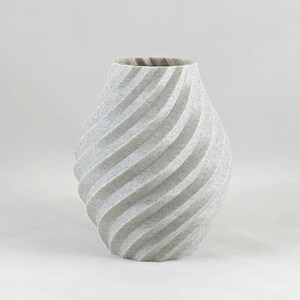 K&ouml;nnte beinhalten: Eine wei&szlig;e Keramikvase mit einem wirbelnden, strukturierten Design. Die Vase ist im modernen, zeitgen&ouml;ssischen Stil.
