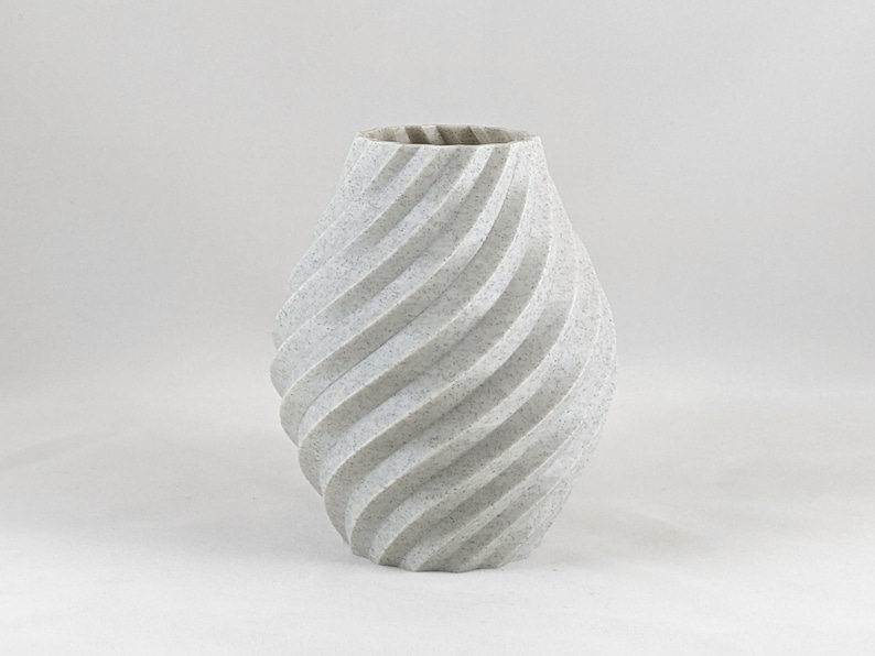 K&ouml;nnte beinhalten: Eine wei&szlig;e Keramikvase mit einem wirbelnden, strukturierten Design. Die Vase ist im modernen, zeitgen&ouml;ssischen Stil.