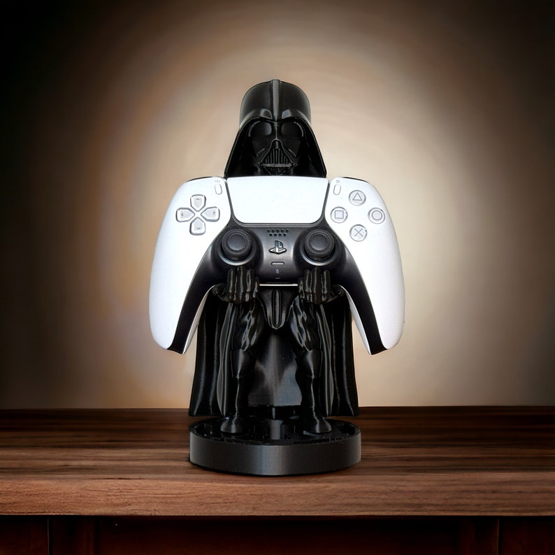 May include: A black Darth Vader figurine holding a white PlayStation 5 controller. The figurine is standing on a black base.