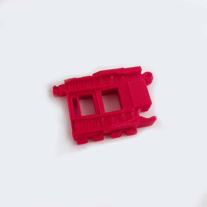 May include: A red plastic train track piece with two openings. The piece is designed to connect to other track pieces.