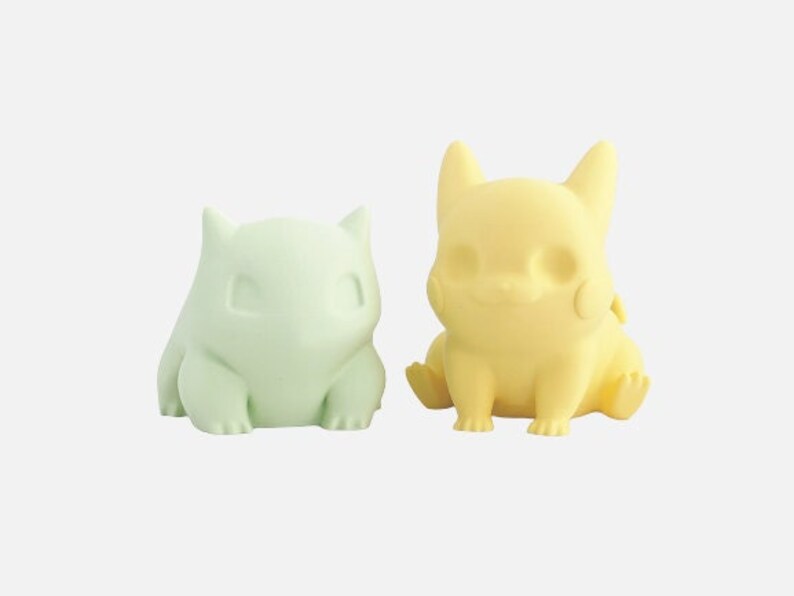 May include: Two small, 3D printed figurines of Pokemon characters. The green figurine is a Bulbasaur and the yellow figurine is a Pikachu.