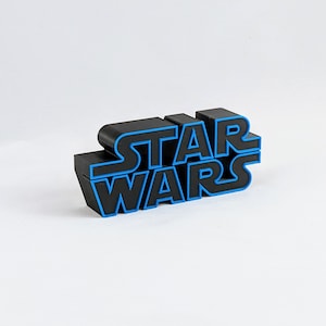 May include: Black plastic "Star Wars" logo with blue outlining. The logo is made of individual letters that are stacked on top of each other.