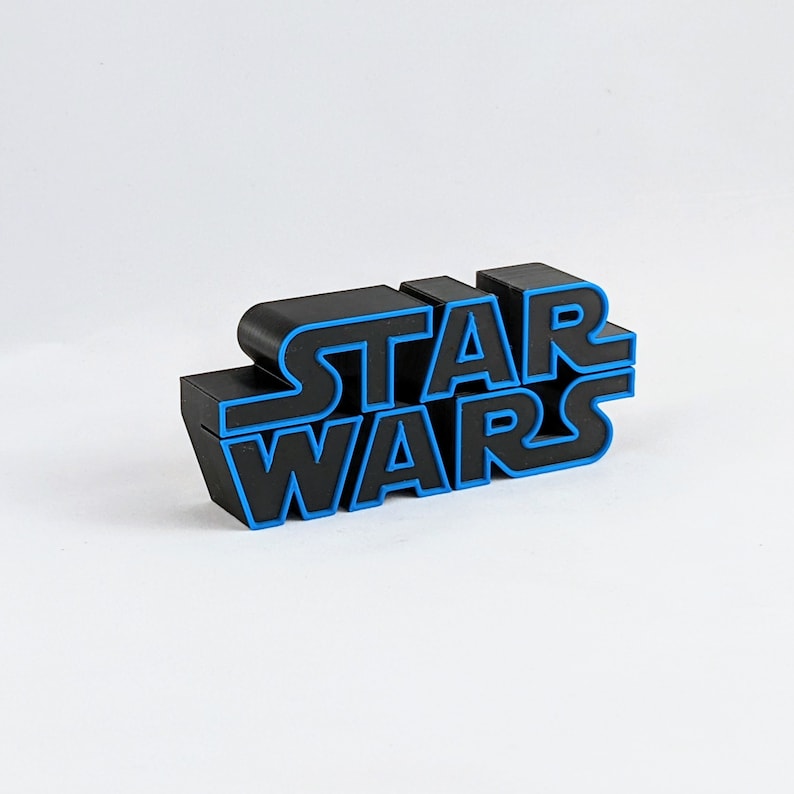 May include: Black plastic "Star Wars" logo with blue outlining. The logo is made of individual letters that are stacked on top of each other.