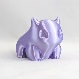 May include: A small, purple, 3D printed figurine of a cartoon character. The figurine has a rounded, slightly chubby body with a large head and small, pointed ears.