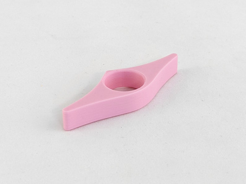 Peut inclure: Un marque-page en plastique rose avec un anneau pour maintenir une page. Le marque-page est en forme de bateau.