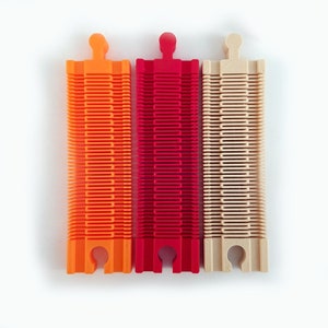 May include: Three plastic track pieces for a toy train set. The track pieces are orange, red, and beige.