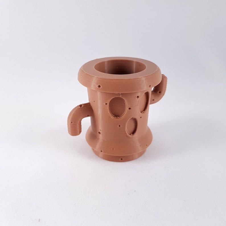 May include: A brown 3D printed planter shaped like a cactus with two arms. The planter has a textured surface and a round opening at the top.