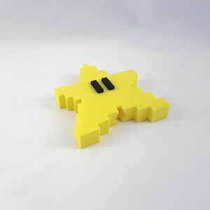 May include: A yellow star-shaped object with two black rectangles in the center. The object is made of a 3D printed material.