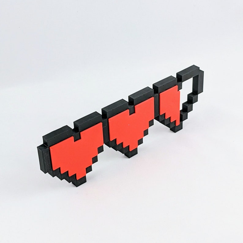 May include: Three red pixelated hearts in a row, with black outlines, representing a video game health bar.