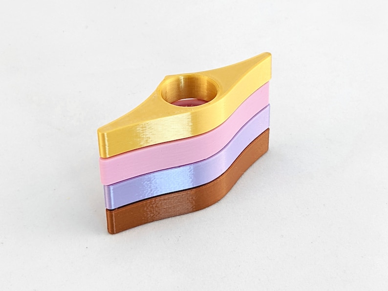 Peut inclure: Un ensemble de trois marque-pages en or, rose et violet. Les marque-pages sont en forme de goutte d'eau avec un trou au centre.