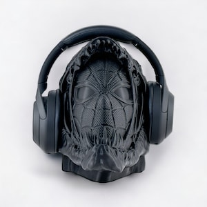 May include: A black 3D printed sculpture of a hooded figure wearing headphones. The figure's face is a stylized depiction of a spider-man mask.