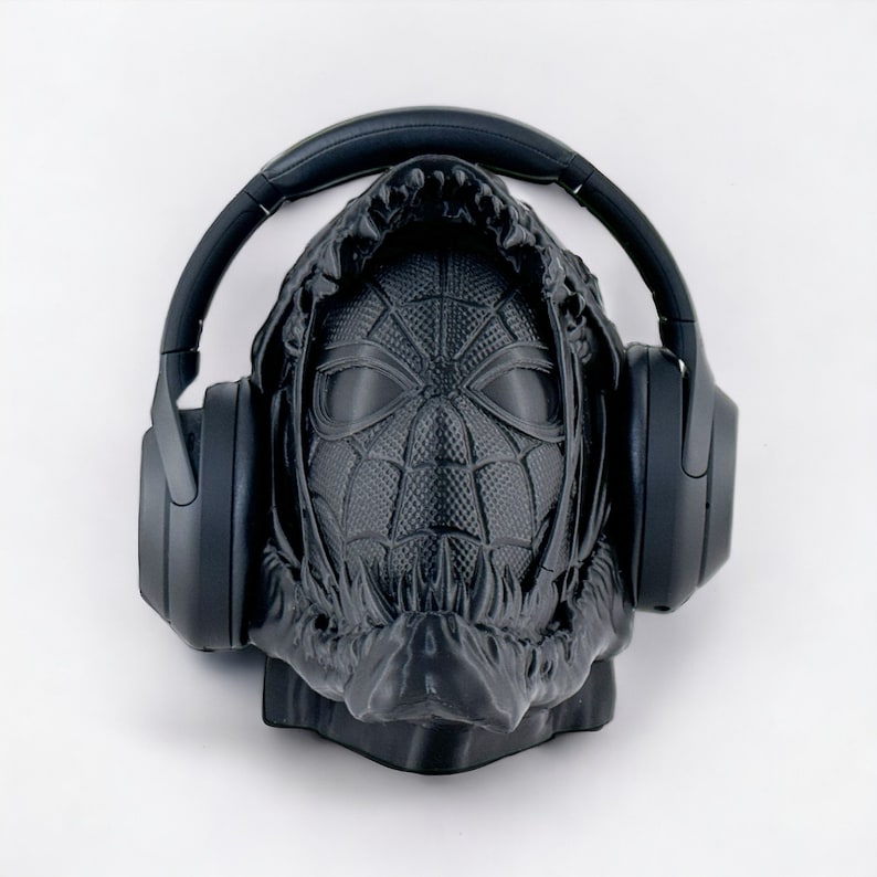 May include: A black 3D printed sculpture of a hooded figure wearing headphones. The figure's face is a stylized depiction of a spider-man mask.