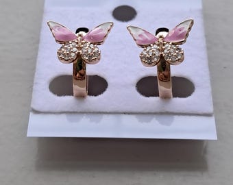 May include: A pair of rose gold butterfly earrings. Each earring features a pink and white enamel butterfly design with a cluster of clear crystals. The earrings are displayed on a white card.