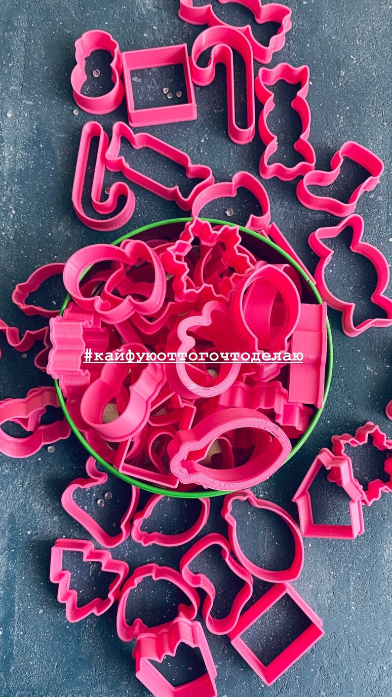 K&ouml;nnte beinhalten: Ein Set rosa Plastik-Ausstecher in einer gr&uuml;nen Dose. Die Ausstecher sind in Form von Weihnachtsb&auml;umen, Sternen, Zuckerstangen, Schneem&auml;nnern und anderen weihnachtlichen Formen. Der Text #кайфуюоттогочтоделаю ist auf der Dose sichtbar.