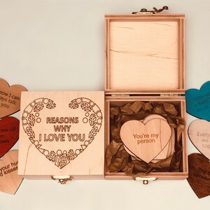 以下が含まれることがあります： 「REASONS WHY I LOVE YOU」の文字が蓋に刻まれた木製のボックスセット。ボックスには「You're my person」などのフレーズが書かれたハート型の木製カードが入っています。愛のメッセージが書かれたハート型のカードがいくつか散らばっています。