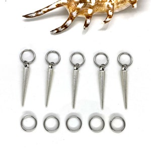 K&ouml;nnte beinhalten: Sechs silberne Haarreifen mit spitzen Enden. Jeder Ring besteht aus einem einzigen St&uuml;ck Metall und hat eine glatte, polierte Oberfl&auml;che. Die Ringe sind in zwei Reihen zu je drei angeordnet, wobei die spitzen Enden nach oben zeigen.
