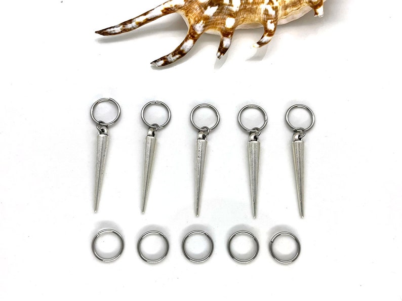 K&ouml;nnte beinhalten: Sechs silberne Haarreifen mit spitzen Enden. Jeder Ring besteht aus einem einzigen St&uuml;ck Metall und hat eine glatte, polierte Oberfl&auml;che. Die Ringe sind in zwei Reihen zu je drei angeordnet, wobei die spitzen Enden nach oben zeigen.