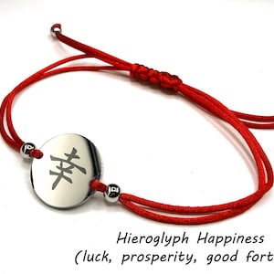 Könnte beinhalten: Rotes Armband mit rundem Silberanhänger. Der Anhänger zeigt ein schwarzes Hieroglyphen-Symbol. Das Armband ist verstellbar mit Gleitknoten und silbernen Perlen. Der Text auf dem Bild lautet "Hieroglyph Happiness".